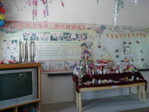 A left behind activity room with a slogan 'care for let behind children, support their healthy development'