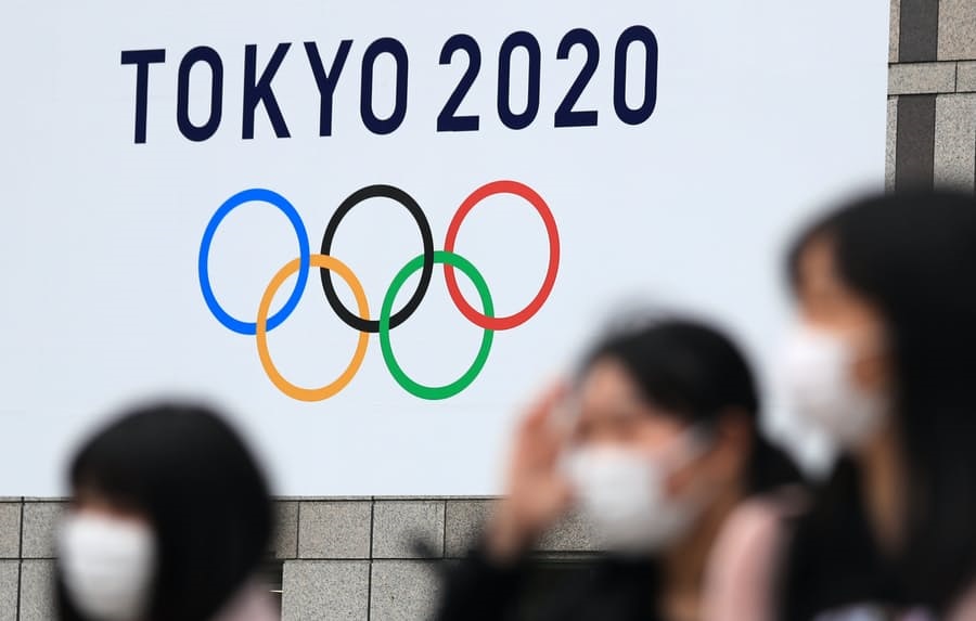 Tokyo 2020 logo with people with facemaks in foreground