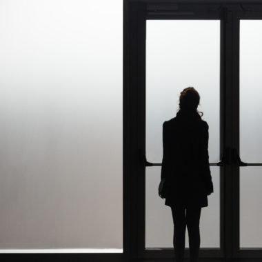 woman waiting in front a glass door in a white room