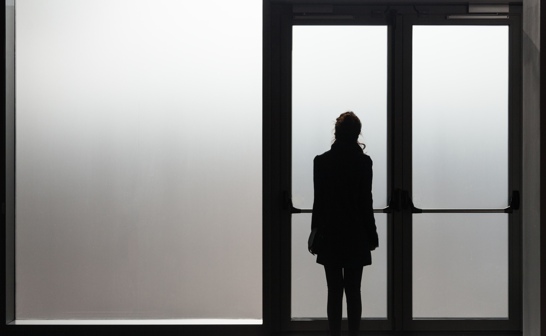 woman waiting in front a glass door in a white room